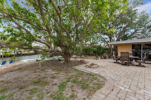 view of yard featuring a water view, an outdoor fire pit, and a patio