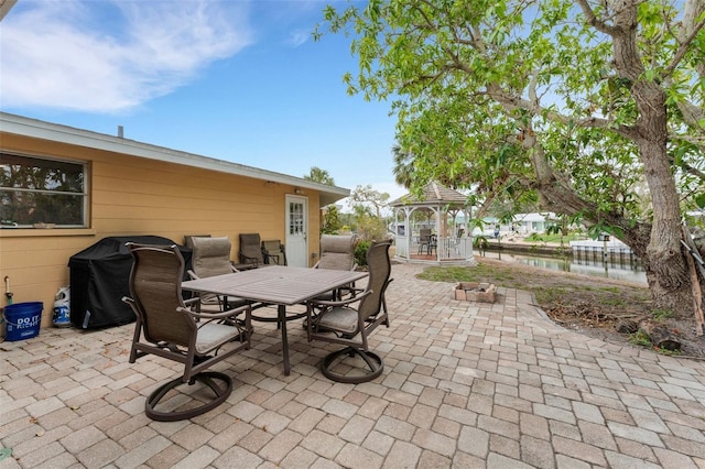 view of patio / terrace with a fire pit, a gazebo, area for grilling, and a water view