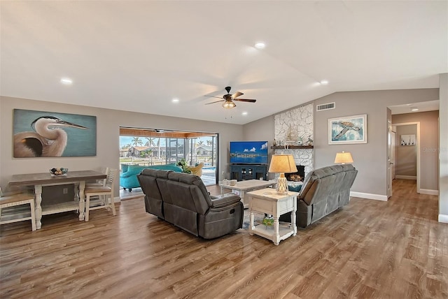 living room featuring ceiling fan, wood-type flooring, lofted ceiling, and a fireplace