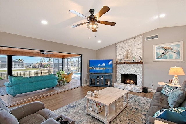 living room featuring hardwood / wood-style flooring, ceiling fan, a fireplace, and vaulted ceiling