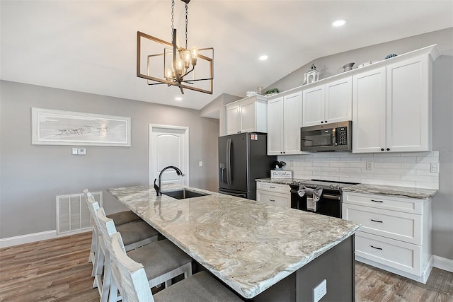 kitchen featuring a kitchen island with sink, sink, pendant lighting, and appliances with stainless steel finishes