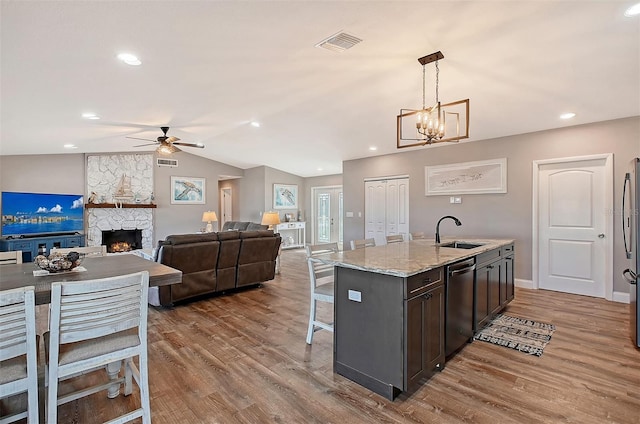 kitchen featuring dark brown cabinets, stainless steel appliances, sink, decorative light fixtures, and an island with sink