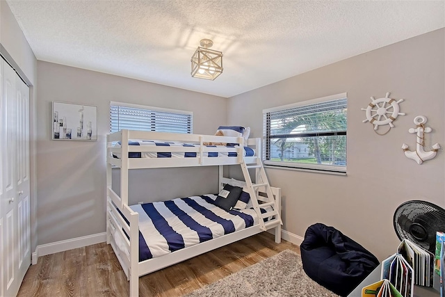 bedroom with multiple windows, hardwood / wood-style flooring, and a closet