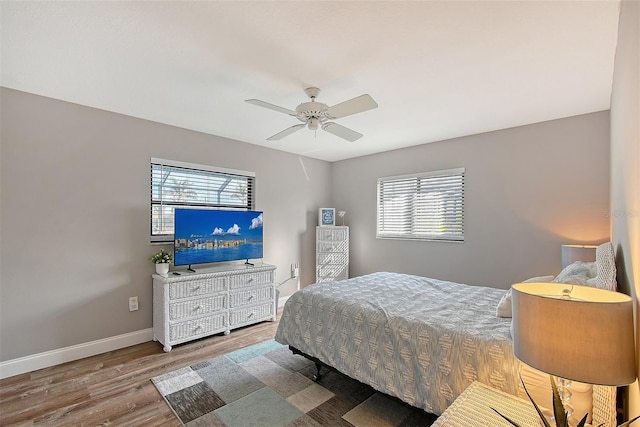 bedroom featuring multiple windows, hardwood / wood-style floors, and ceiling fan