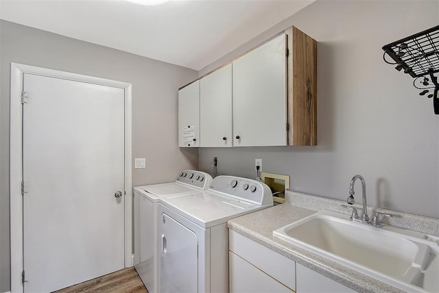 washroom with cabinets, washing machine and dryer, sink, and light hardwood / wood-style flooring