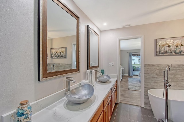 bathroom with a tub, tile patterned flooring, vanity, and tile walls