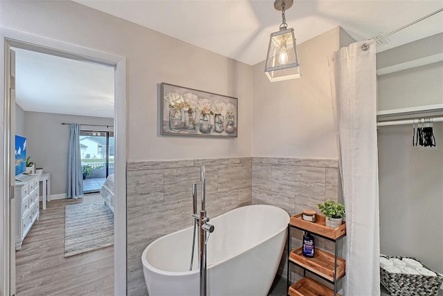 bathroom featuring a bathing tub, hardwood / wood-style floors, and tile walls