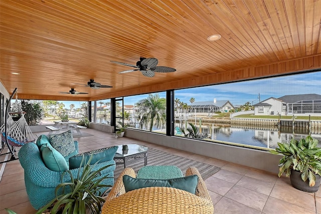 sunroom featuring ceiling fan, a water view, and wooden ceiling