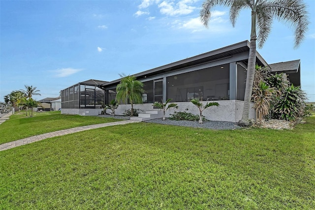 back of property with a sunroom and a lawn