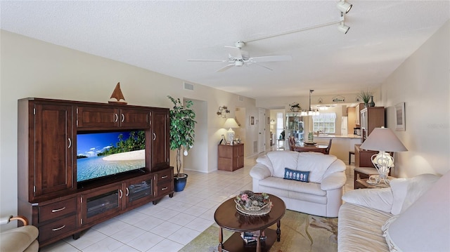 living room featuring ceiling fan, light tile patterned flooring, and a textured ceiling