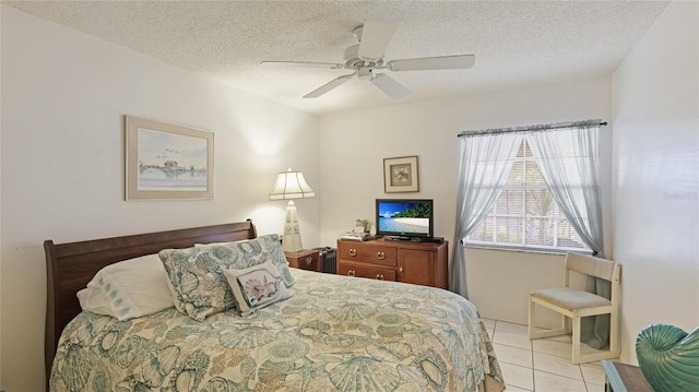 bedroom featuring ceiling fan, light tile patterned floors, and a textured ceiling