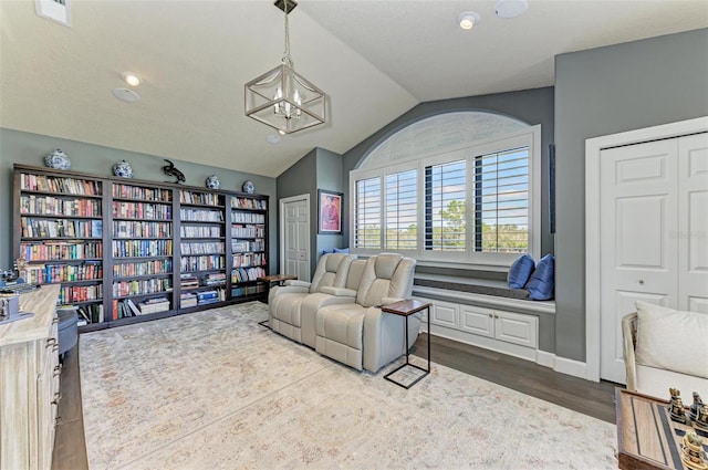 living area with hardwood / wood-style flooring, vaulted ceiling, and a chandelier