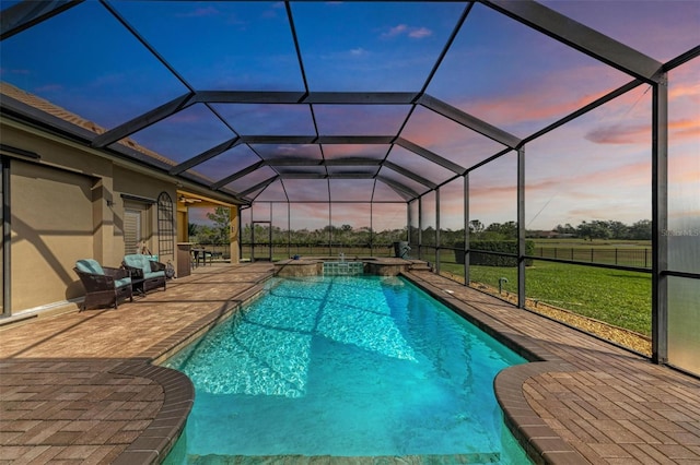 pool at dusk with an in ground hot tub, a lanai, a lawn, and a patio area