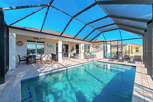 view of swimming pool featuring a patio, glass enclosure, and ceiling fan