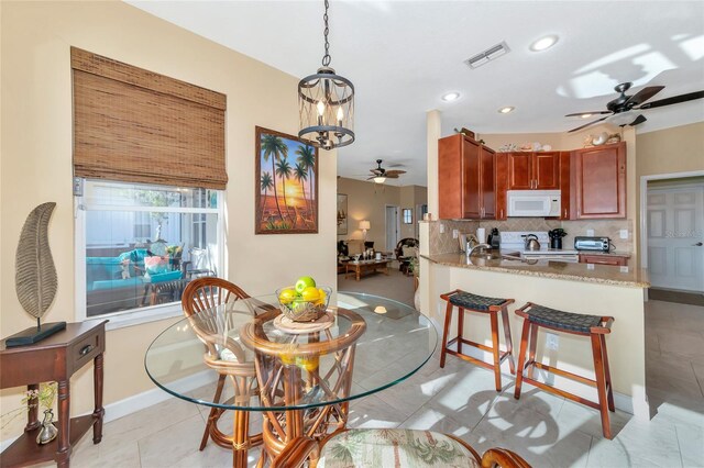 dining space with light tile patterned floors and ceiling fan with notable chandelier