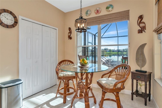 dining area with a chandelier, light tile patterned floors, and a water view