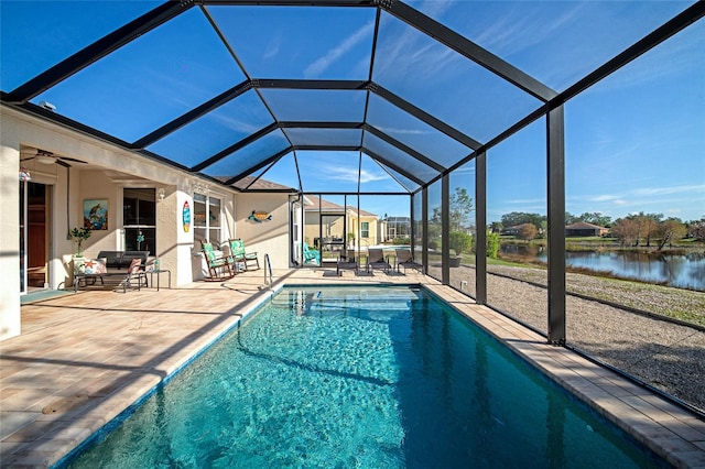 view of swimming pool with glass enclosure, ceiling fan, a water view, and a patio