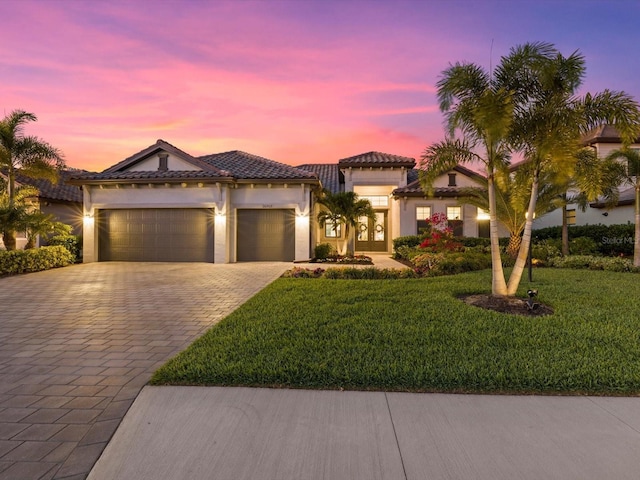 mediterranean / spanish house with a garage and a yard