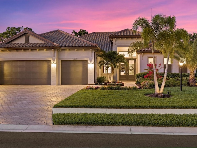 mediterranean / spanish-style house featuring french doors, a garage, and a lawn