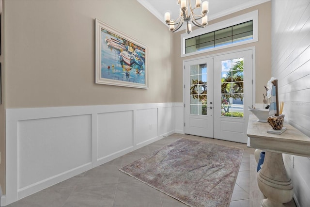 foyer featuring french doors, ornamental molding, and a notable chandelier