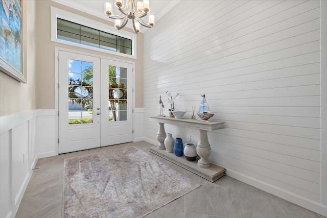 tiled foyer featuring a notable chandelier, crown molding, and french doors