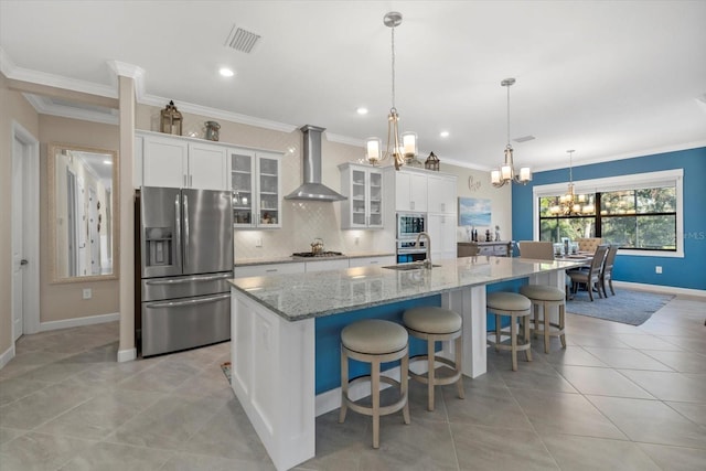 kitchen featuring wall chimney exhaust hood, white cabinetry, stainless steel appliances, and a kitchen island with sink