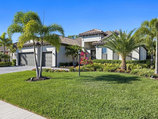 mediterranean / spanish home featuring a garage and a front lawn