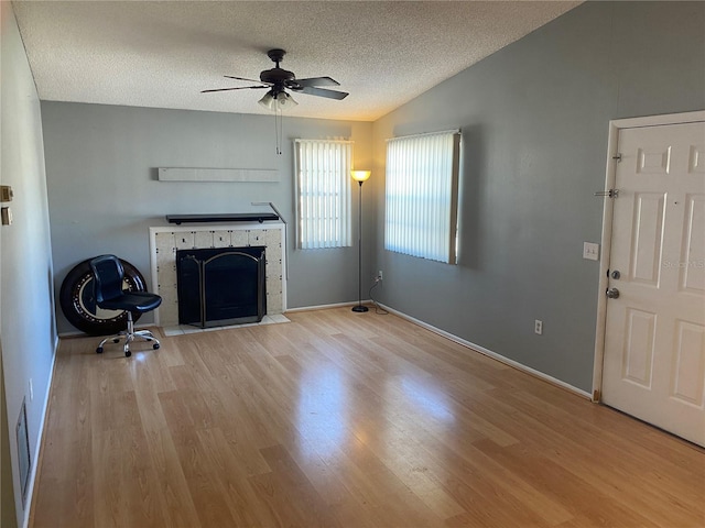 unfurnished living room featuring ceiling fan, vaulted ceiling, light hardwood / wood-style flooring, and a textured ceiling