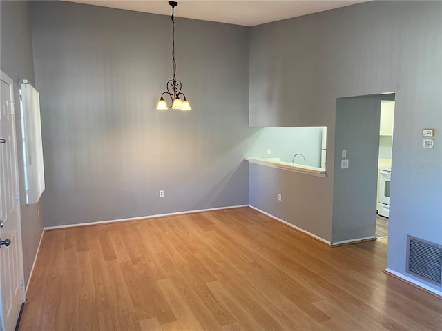 unfurnished room with an inviting chandelier and light wood-type flooring