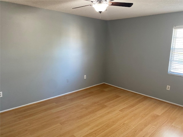 unfurnished room with ceiling fan, a textured ceiling, and light wood-type flooring