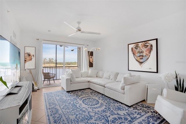 living room with ceiling fan, a water view, and light tile patterned floors