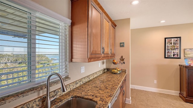 kitchen with light stone countertops, light tile patterned floors, dishwasher, and sink