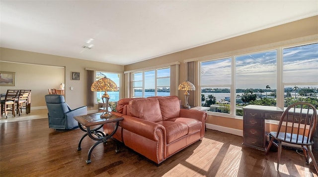 living room with dark hardwood / wood-style flooring and a water view