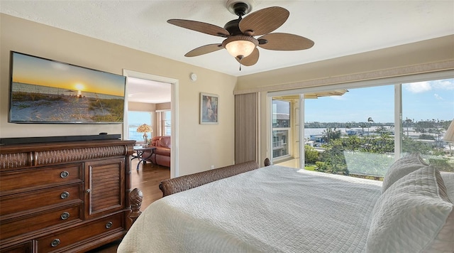 bedroom with access to exterior, ceiling fan, and dark wood-type flooring