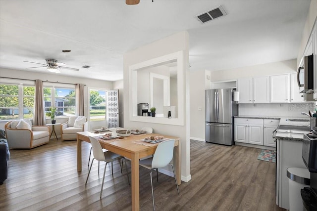 dining room featuring ceiling fan, dark wood-type flooring, and sink