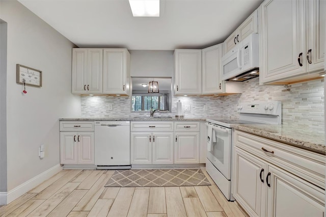 kitchen with white cabinets, white appliances, light wood-type flooring, decorative backsplash, and light stone countertops