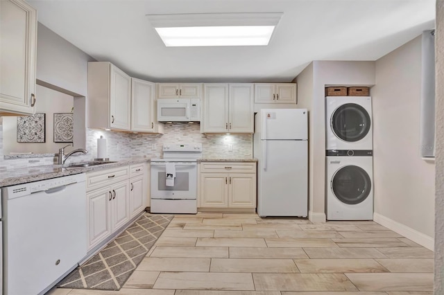 kitchen featuring sink, light stone counters, white appliances, light hardwood / wood-style floors, and stacked washer and dryer