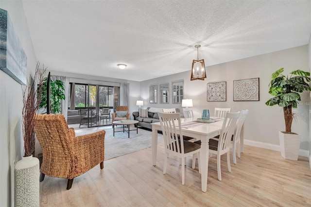 dining area featuring a textured ceiling, light hardwood / wood-style floors, and a chandelier