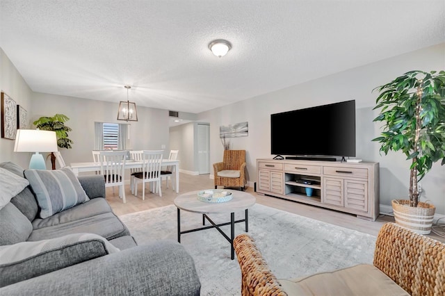 living room with a textured ceiling, light hardwood / wood-style flooring, and a chandelier