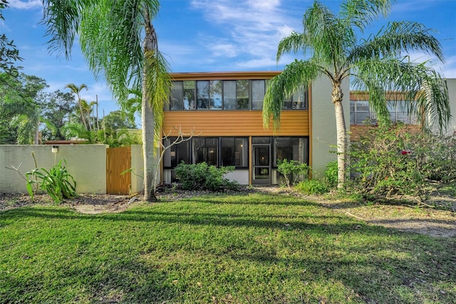 rear view of house with a yard and a sunroom