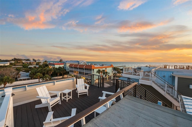 deck at dusk featuring a water view