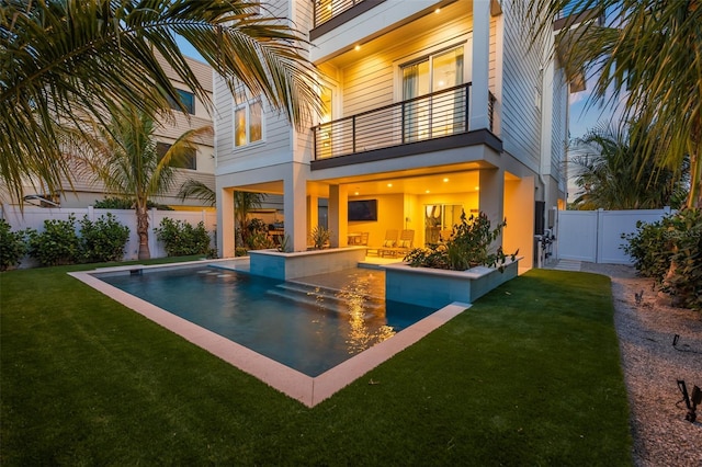 rear view of house with a yard, a balcony, a patio, and a fenced in pool