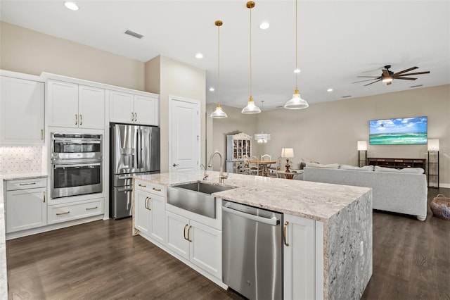 kitchen featuring appliances with stainless steel finishes, white cabinets, hanging light fixtures, and sink