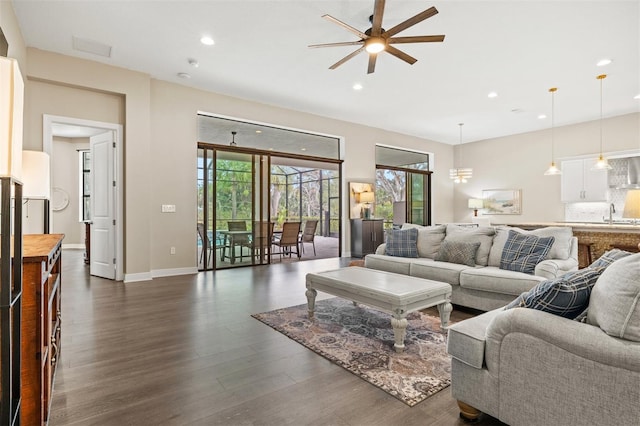 living room featuring ceiling fan, dark wood-type flooring, and sink