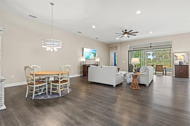 living room with ceiling fan with notable chandelier and dark wood-type flooring