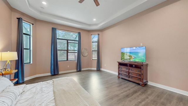 bedroom featuring ceiling fan, hardwood / wood-style flooring, and a tray ceiling