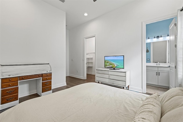 bedroom with ensuite bathroom, dark hardwood / wood-style floors, sink, a spacious closet, and a closet