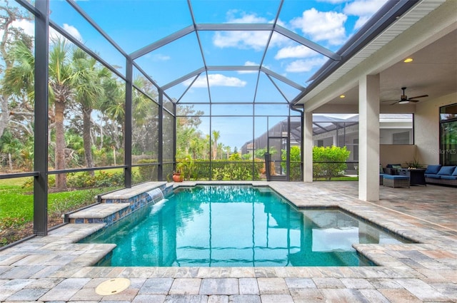 view of swimming pool featuring ceiling fan, a patio area, pool water feature, glass enclosure, and an outdoor hangout area