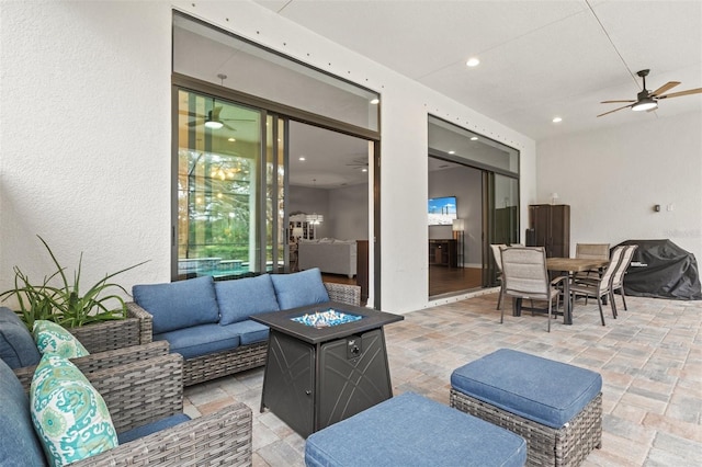 view of patio / terrace featuring ceiling fan and an outdoor living space with a fire pit