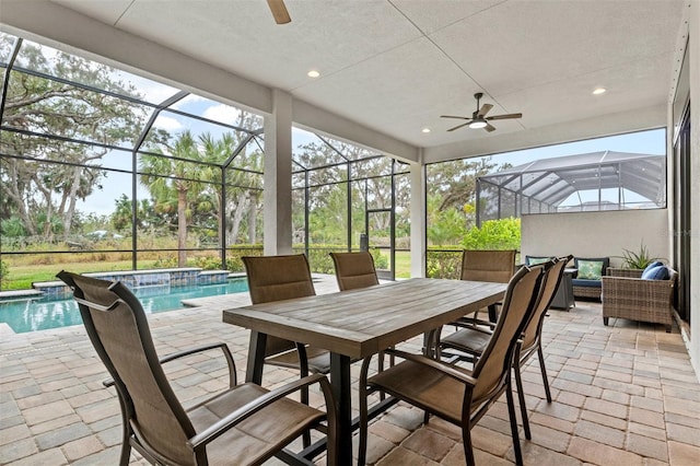 view of patio with ceiling fan, a swimming pool with hot tub, pool water feature, and glass enclosure